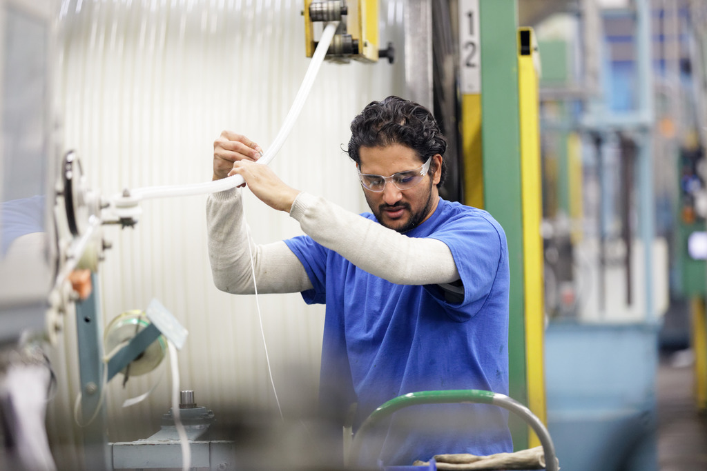 A diverse male manufacturing employee working at the Uponor PEX extruder machine