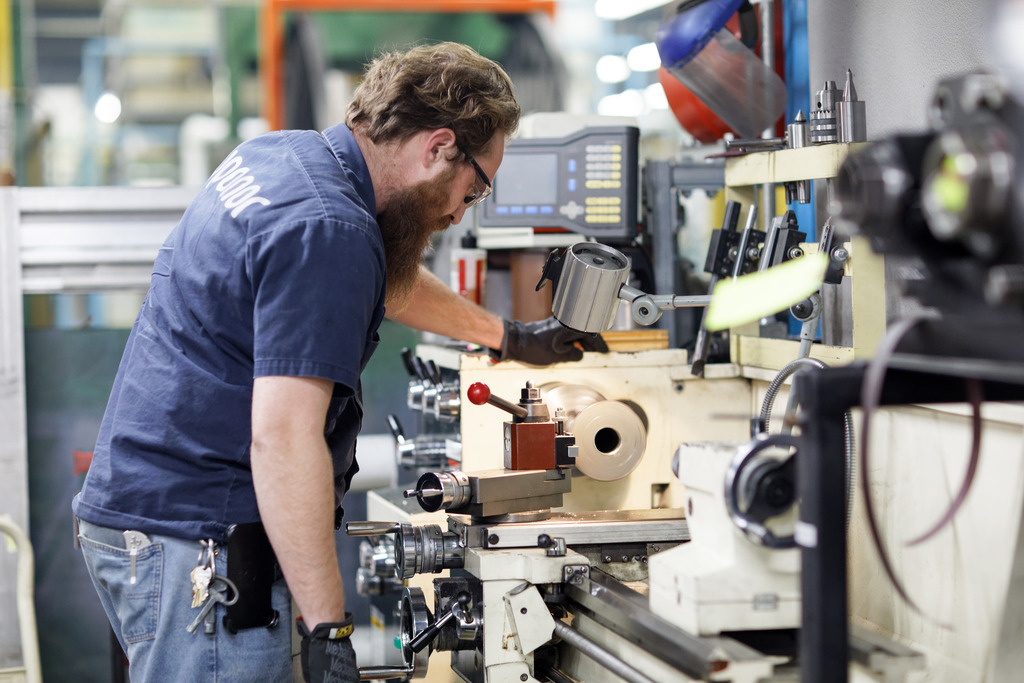 Un empleado de fábrica operando una máquina de extrusión de tuberías Uponor PEX de Uponor en Apple Valley, Minnesota
