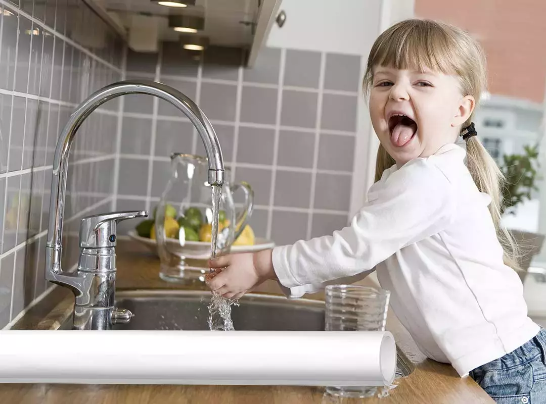 flicka tvättar händer under tappvattenkran