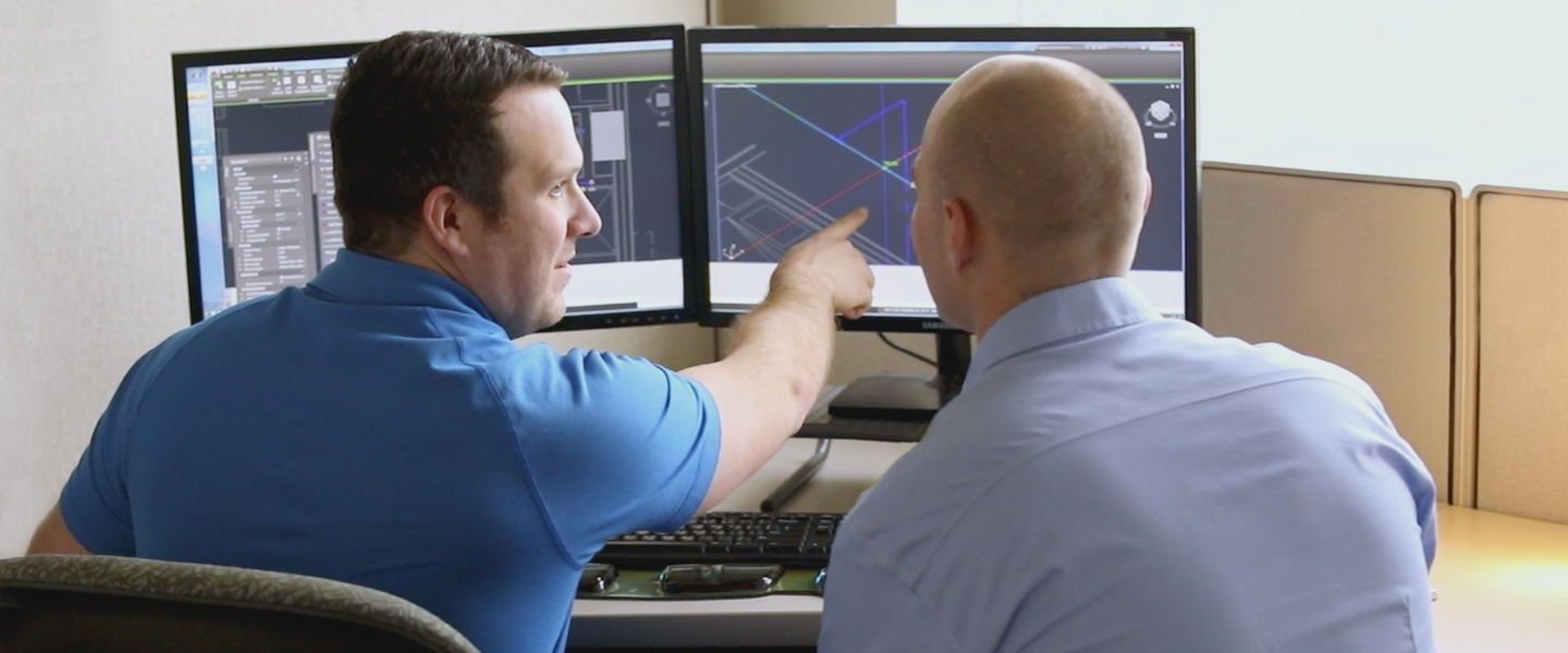 A photo of a male design services representative showing another male an uponor BIM design