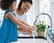 Caring mom shows her preschool age daughter how to wash hands. They are washing hands in the kitchen sink.