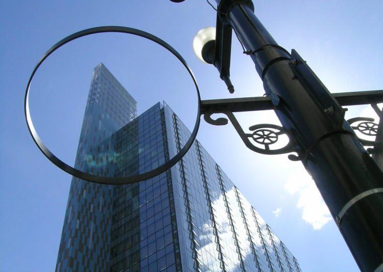 Exterior photo of Manitoba Hydro Place, framed through the ring in a nearby lamppost.